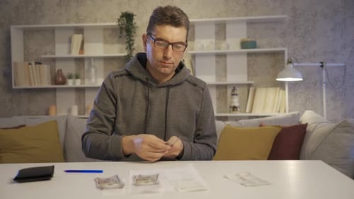 Man Counting Money at Table in Home