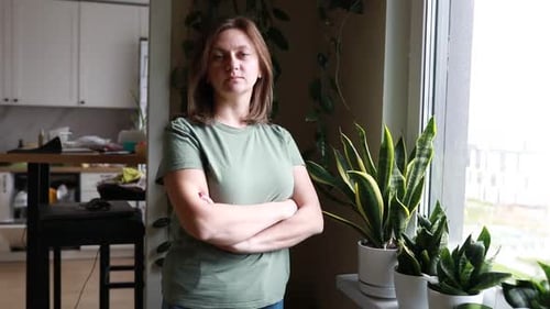 Woman Standing in Front of Window Next to Potted Plant