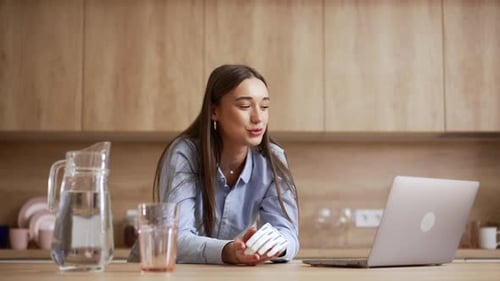 Woman with Prosthetic Hand Using Laptop in Kitchen