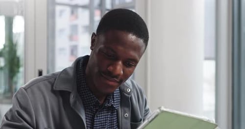 Creative, black man and reading on tablet in office for research, editor feedback