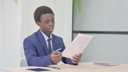 Young Adult Reading Documents in Office Environment