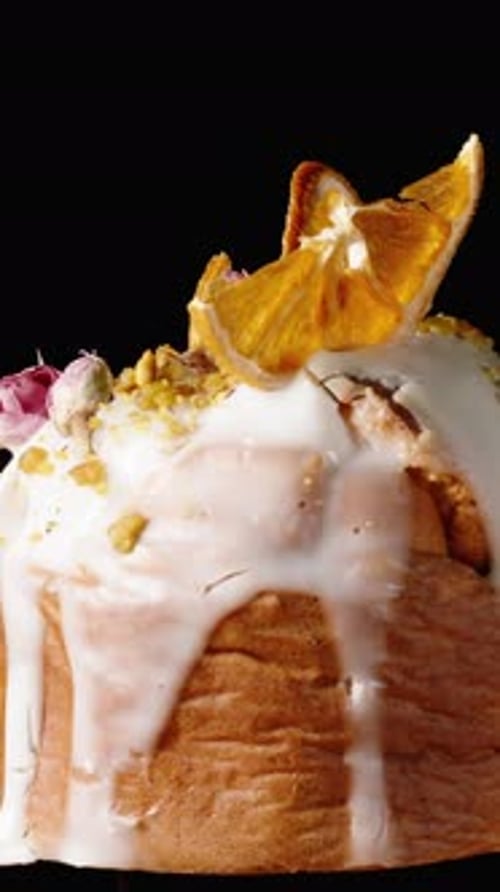 Vertical video. Cake on a black background with drips of white icing and decorated on top