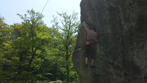 Young Man Climbing Steep Wall of Rocky Mountain