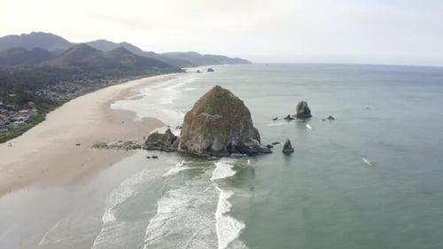Drone flying towards haystack rock in canon beach oregon. 4k aerial of west coast beach