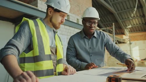 Foreman and Building Contractor Working with Floor Plans at Construction Site