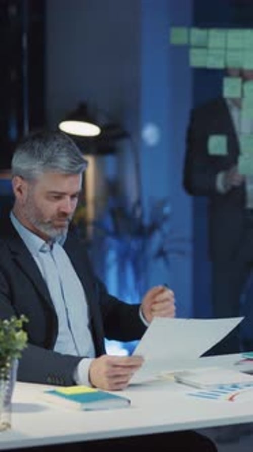 A Business Professional Methodically Reviewing Important Documents in a Modern Office Space