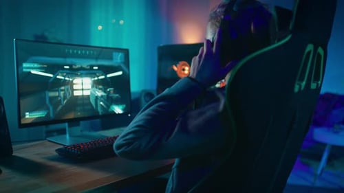 Man Playing First Person Shooter in Blue Lit Room