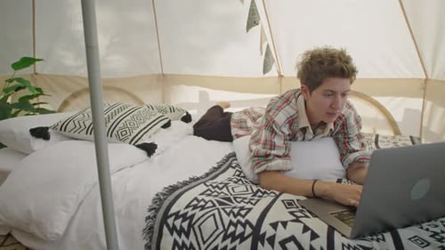 Jovem mulher descansando em tenda de glamping e usando laptop