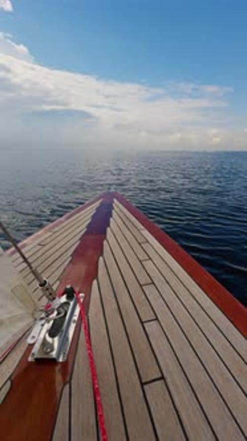 a proa de um lindo veleiro de madeira navegando em águas calmas, o lado vermelho brilhante do barco