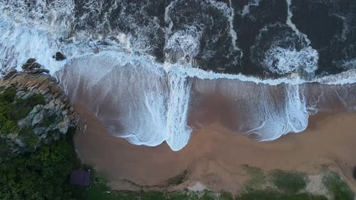 Slowmo Aerial Topdown View of a Sandy Beach Being Hit By Foamy Storm Waves