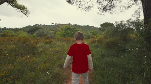 Young Boy Walking Alone on a Path in Nature