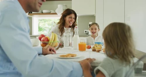 Family Laughing Together at Breakfast Table