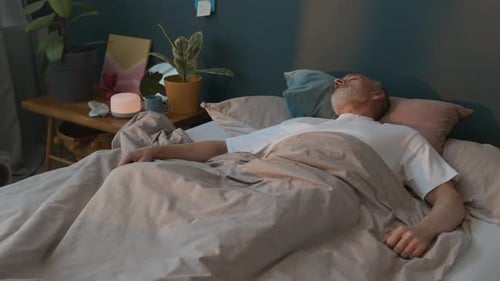 Homme âgé dormant dans une chambre confortable
