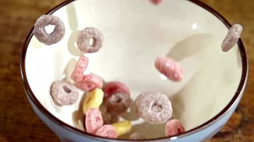 Multi-Colored Breakfast Cereal Loops Falling into White Bowl
