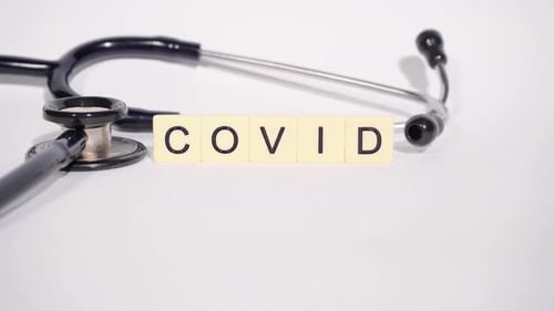 Stethoscope and COVID Blocks on White Surface