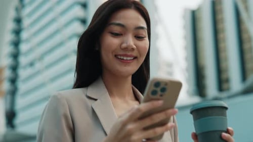 Portrait of Pretty Woman with Coffee Cup Holding Smartphone on City Street