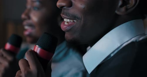 Man and Woman Singing Karaoke Together Indoors at Night