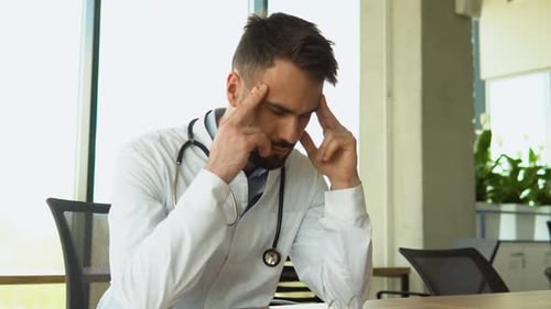 Stressed Doctor in White Coat Rubbing Temples