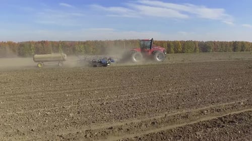 Big red combine working on the field cultivating and applying nitrogen ASP
