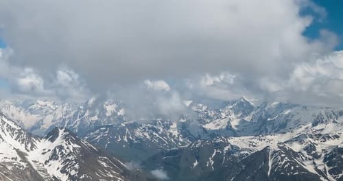 Air flight through mountain clouds over beautiful snow-capped peaks of mountains and glaciers.