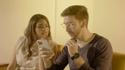 Woman and Man Looking at Smartphone on Couch