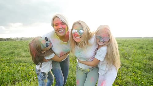 Women and Children Embrace Covered in Colorful Powder