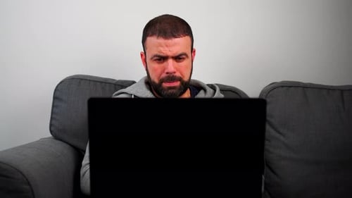 Man Works on Laptop While Sitting on Couch