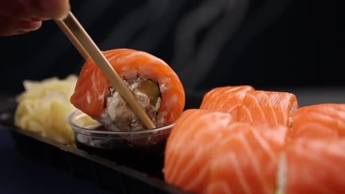 Sushi Roll Being Dipped in Soy Sauce