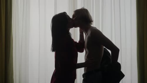 Romantic Couple Embracing and Kissing in Front of Window