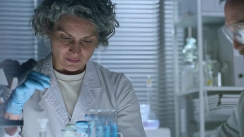Chemikerin experimentiert im Labor mit blauer Flüssigkeit