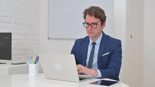 Man Wearing Suit Typing on Laptop in Office