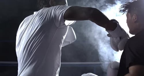 Fighter punching opponent in the face captured in slow-motion with dramatic impact inside boxing