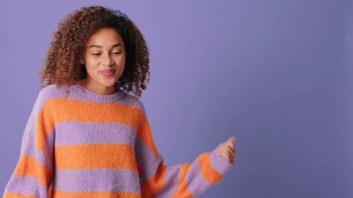 Happy young woman dancing near copy space over, on lilac background in studio