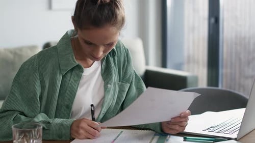 Woman Working at Home Writing in Notebook