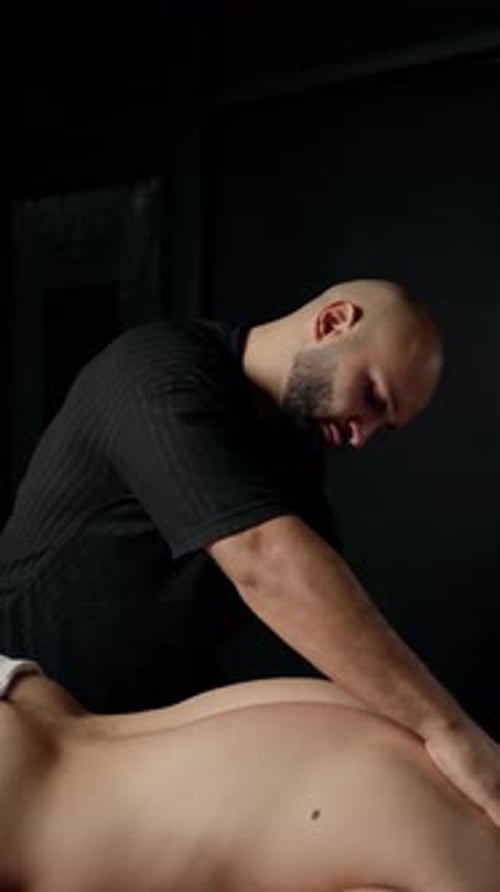 Man Massaging Someone Lying on Massage Table
