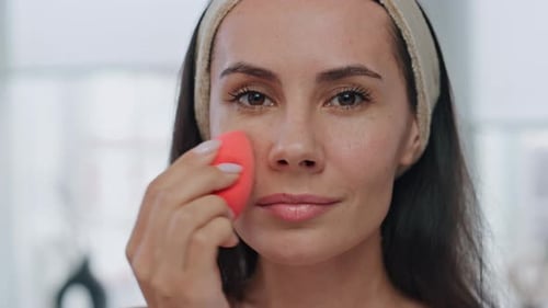 Young Woman Applies Makeup with Sponge on Face