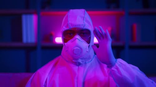 Man in Protective Suit Works During Pandemic in a Neonlit Space