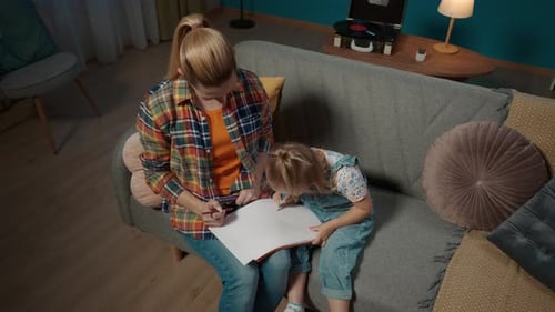Woman and Child Draw Together on Sofa