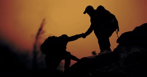 Sunset, mountain and silhouette of men helping on cliff for view in nature with camping backpack