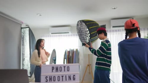Asian woman model being photographed by cameraman in a photography studio.