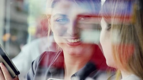 4k video footage of two attractive businesswomen sitting in a cafe and using a digital tablet