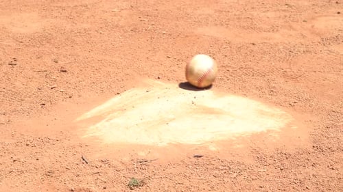 Baseballs rolling across home plate