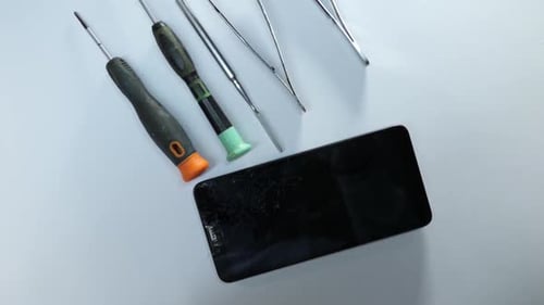 Broken Smartphone with Cracked Screen and Tools