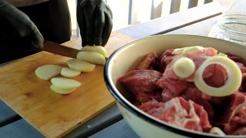 Person Preparing Meat with Onions on Table