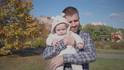 A Joyful Father and His Baby Delightfully Enjoying a Beautiful Sunny Day in the Park