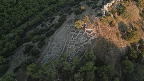 Luftaufnahme einer archäologischen Stätte auf einem baumbedeckten Hügel bei Sonnenaufgang