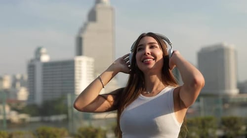 Porträt einer fröhlichen Frau, die Musik hört, wenn sie an einem sonnigen Tag am Wasser entlang geht