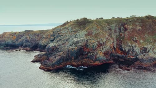 Distancing from the grey unapproachable rocks at the shore of the sea.