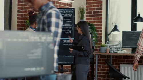 IT-Startup-Mitarbeiter vergleicht Codefehler auf dem Wanddisplay mit dem Tablet