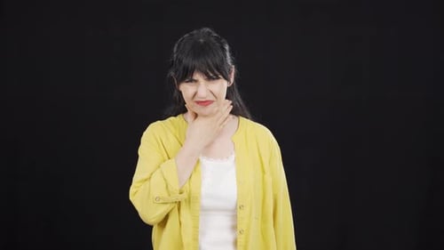Woman Clutches Sore Throat in Discomfort
